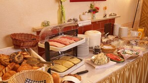 A buffet with various food items, including meats, cheeses, and breads, arranged on a table with a golden draped tablecloth.