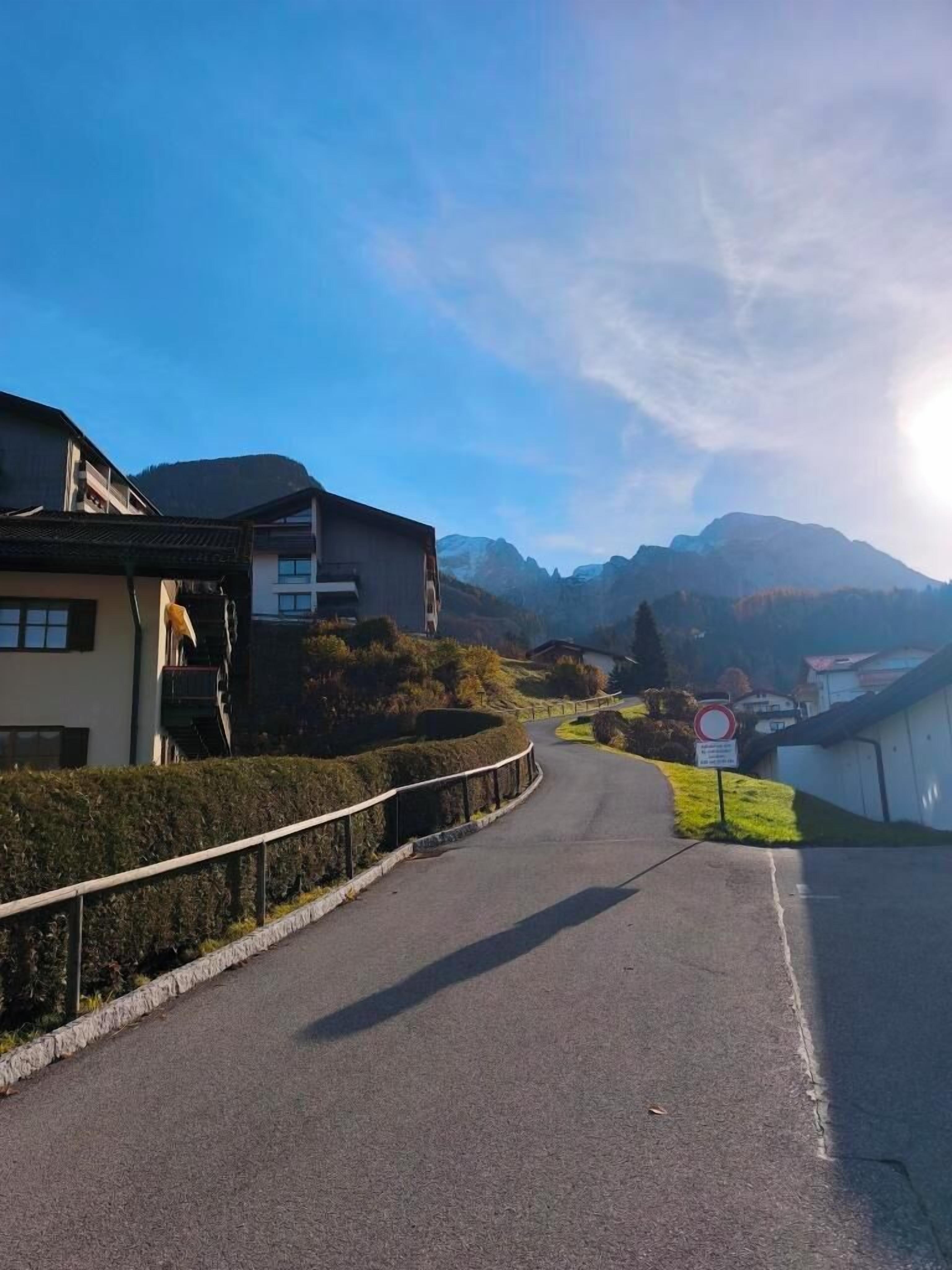 Une route menant à un quartier résidentiel, avec des maisons et une montagne en arrière-plan.