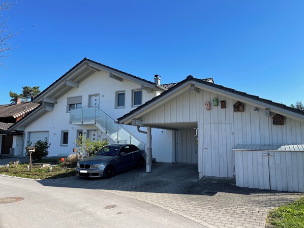 Une maison à deux étages avec un garage, une voiture garée devant et un petit jardin.