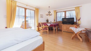 Una habitación de hotel con cama, escritorio con televisor, mesa de comedor y sofá.