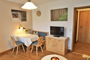 A dining area with a table, chairs, a TV, and a cabinet.