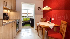 Un espacio habitable compacto con kitchenette, comedor y una pared de acento roja.