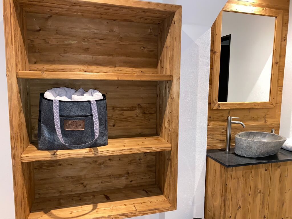 Ein Holzregal mit einer grauen Tragetasche und einem Steinkonstruktion-Waschbecken.