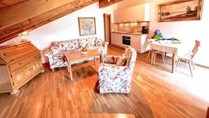 Un appartement-loft chaleureux avec un plafond en bois, un canapé à motifs floraux, une table à manger et un coin cuisine.