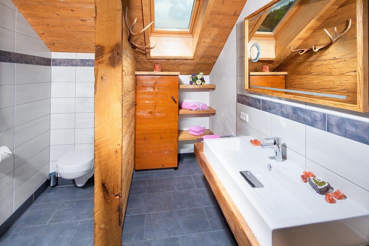 Un baño moderno con tragaluz, detalles de madera, una bañera grande y un tocador con espejo.