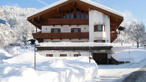 A large, multi-story building with a wooden facade and a sign reading "Gästehaus Alpenrose." - (8) Zwei-Raum-Ferienwohnung 41qm, Dusche/WC, Extra-Schlafraum, Küche, 2 Balkone (Reit im Winkl)