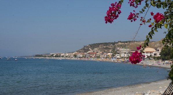 A coastal town with a beach, boats, and buildings.