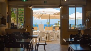 En restaurang med uteservering, bord, stolar och parasoller.