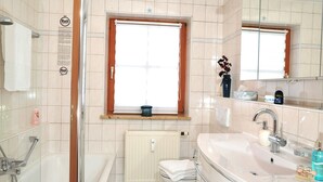 Une salle de bain moderne avec une douche à l’italienne, un grand lavabo et une fenêtre offrant une belle vue.