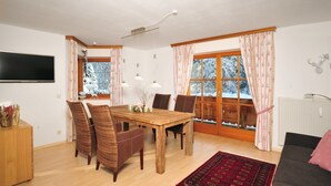 Un coin repas avec une table en bois, des chaises en osier et un tapis rouge.