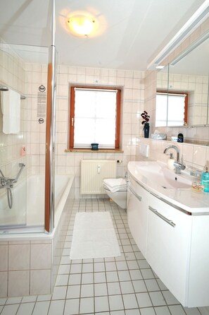 A bathroom with a bathtub, a sink, and a window.