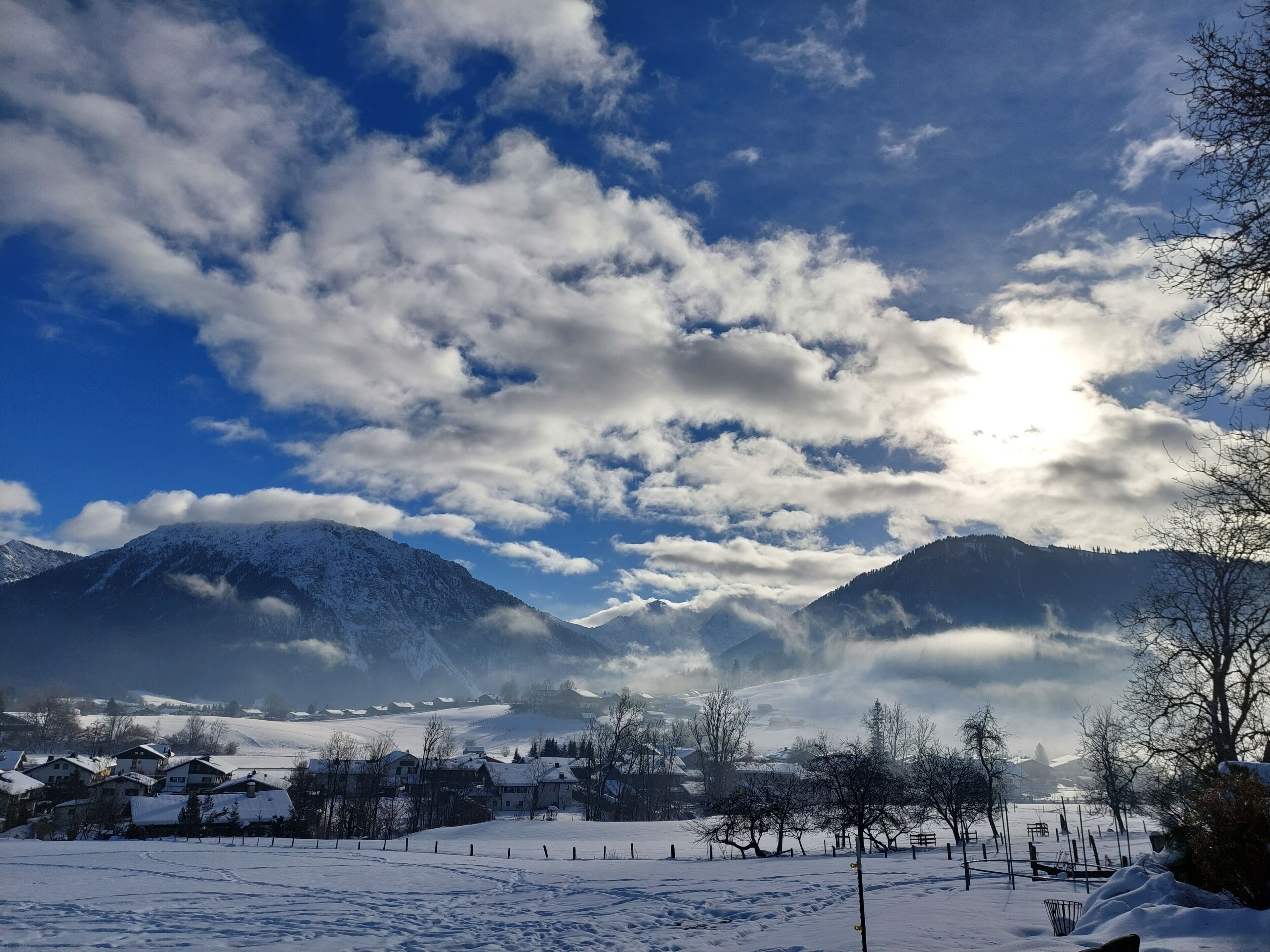 Paesaggio innevato con montagne, un villaggio e cielo sereno.