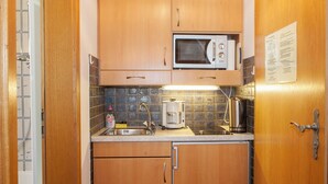 A compact kitchen with wooden cabinets, a microwave, a coffee maker, and a sink. - Ein-Raum-Ferienwohnung (3) 27qm, Bad/WC, Küchenzeile, Balkon (Reit im Winkl)
