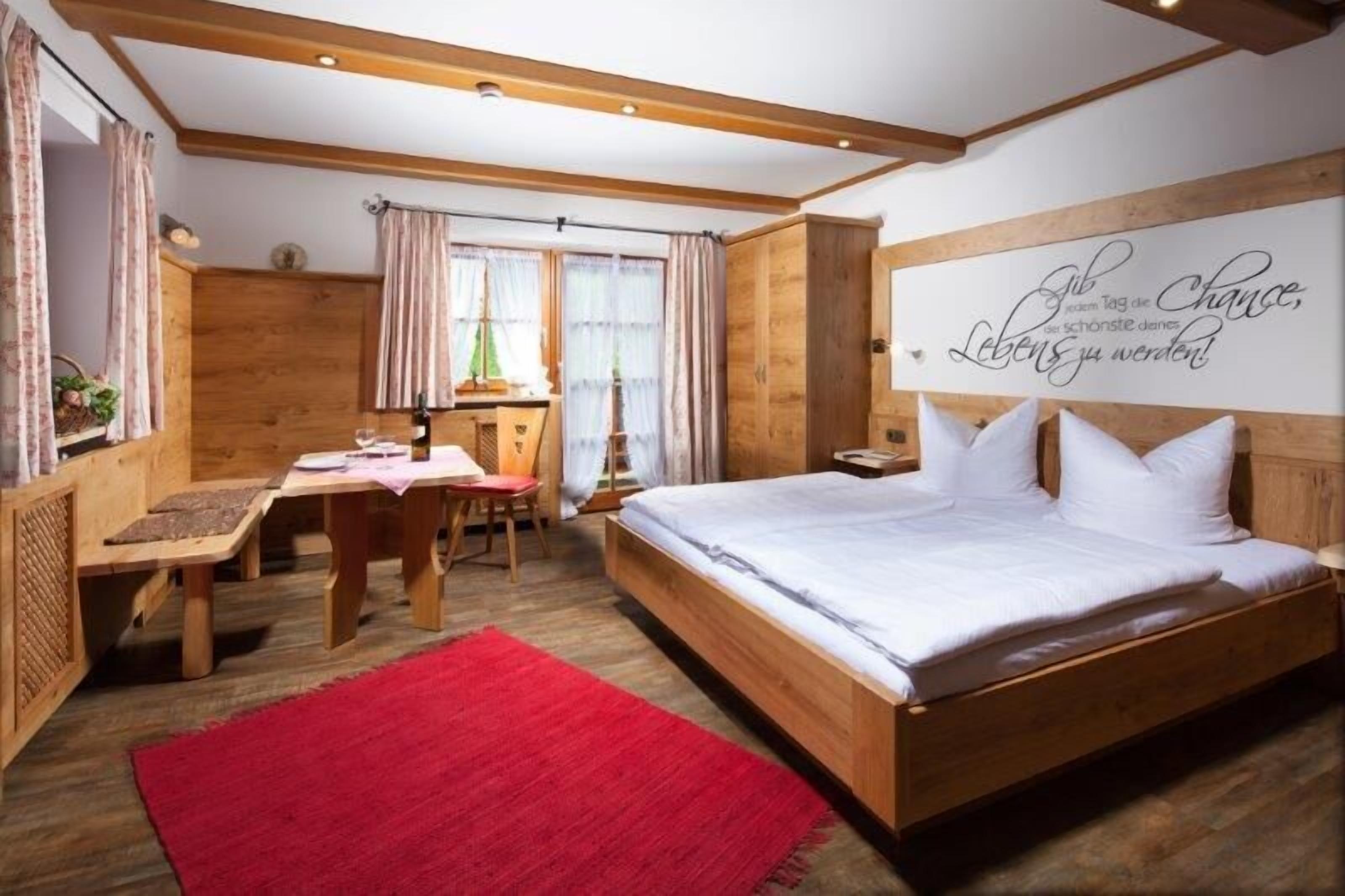 Ein Schlafzimmer aus Holz mit Bett, Schreibtisch und einem roten Teppich.