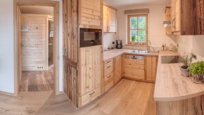 Une cuisine dotée de meubles en bois, d’un four encastré et d’une fenêtre donnant sur un paysage verdoyant.