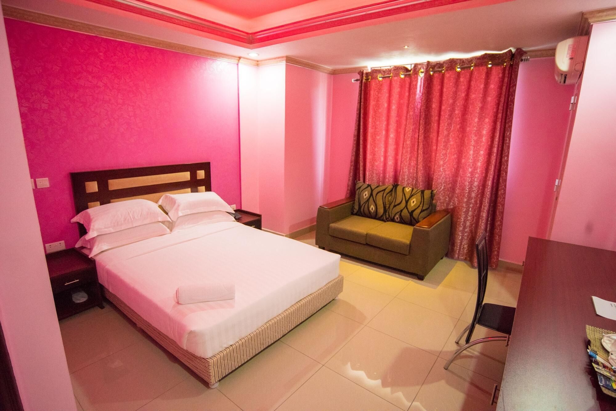 Habitación de hotel con cama, sofá, escritorio y cortina.