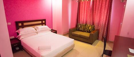 A hotel room with a large bed, a sofa, and a desk.