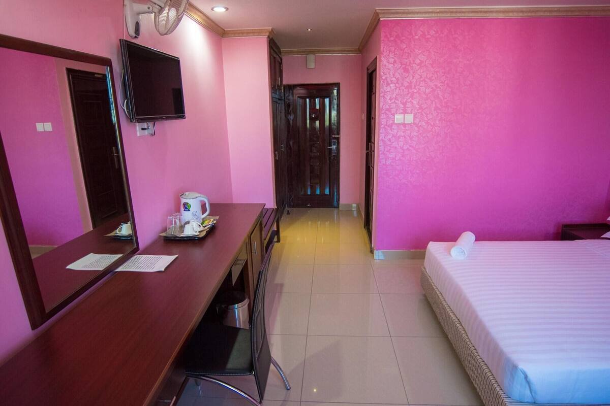 Une chambre d’hôtel équipée d’un bureau, d’un lit, d’une télévision et d’une porte donnant sur une autre pièce.