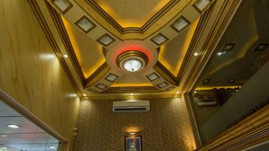 Um hall amplo com pé-direito alto, um skylight circular central, iluminação embutida e um quadro na parede.