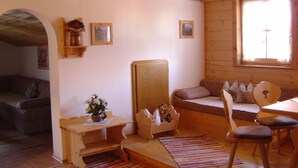Interior acogedor de una cabaña con techo de madera, un sofá, una mesa de comedor y una ventana con vistas.