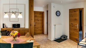 Un coin repas avec une table en bois, des chaises, un vase de fleurs et une horloge au mur.