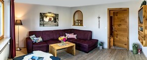 Ein Wohnzimmer mit einem dunkelroten Sofa, einem Holztisch und einer Lampe.