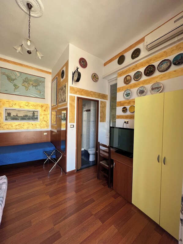 A room with a wooden floor, a blue sofa, a TV, and a yellow wardrobe.