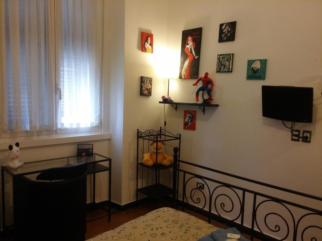 Ein Schlafzimmer mit Bett, Schreibtisch, Stuhl, Fernseher und Wanddekorationen, darunter Poster und Figuren.