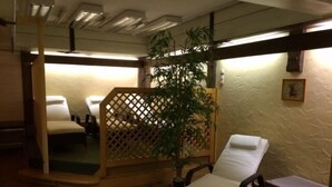 Een kamer met een bed, een klein tafeltje, een stoel en een plant.