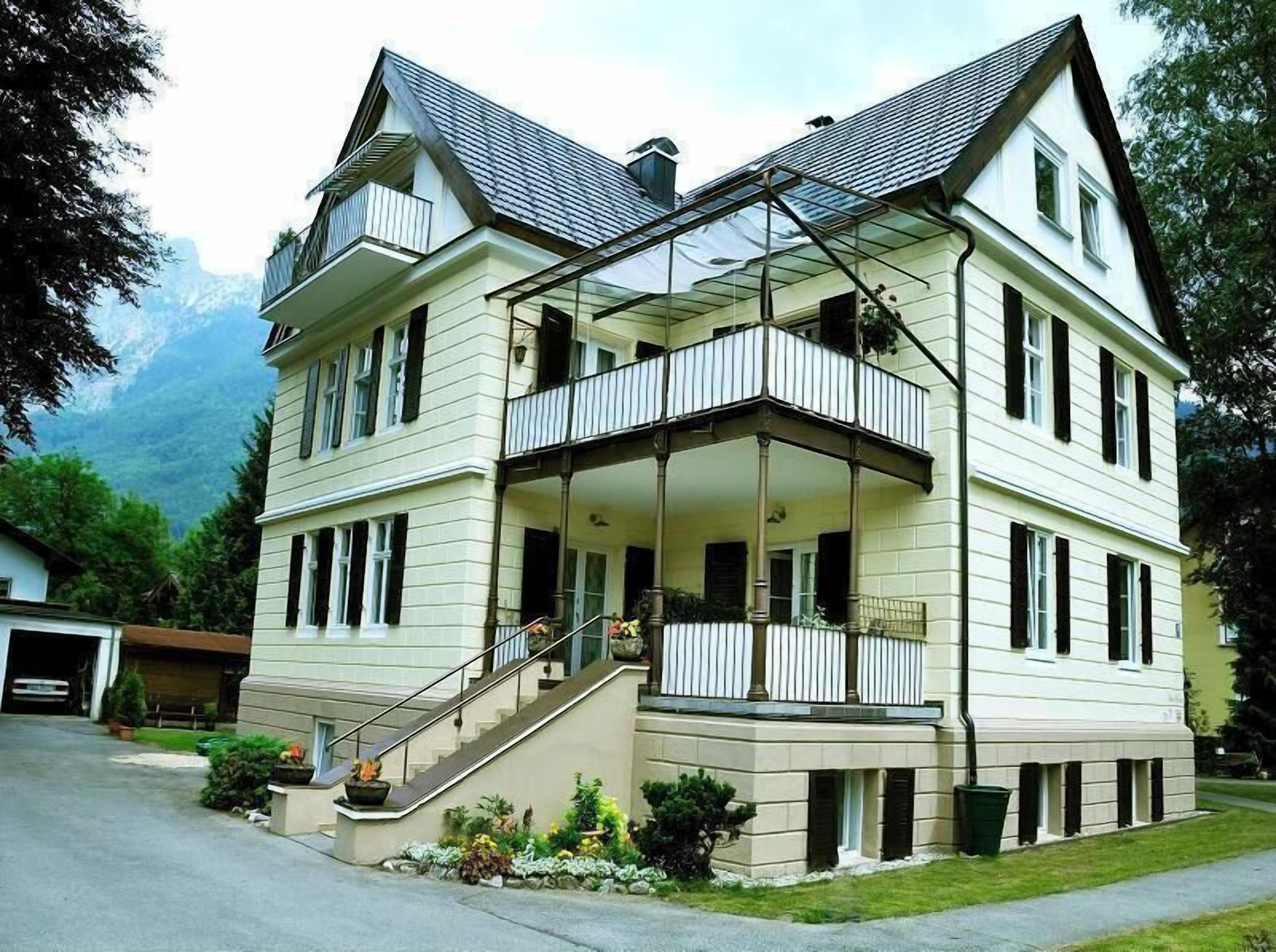 A two-story house with a balcony, a covered porch, and a staircase leading to the entrance.