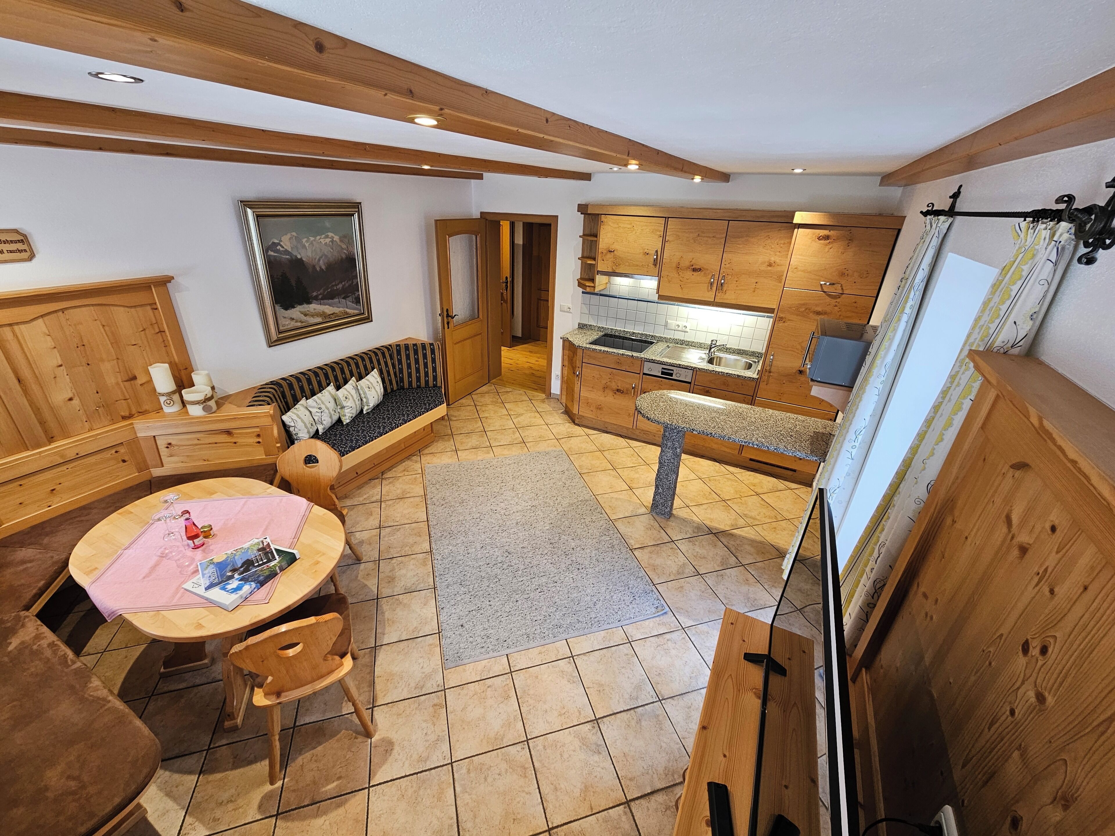 A kitchen with wooden cabinets, a dining table with chairs, a sofa, and a kitchen island.