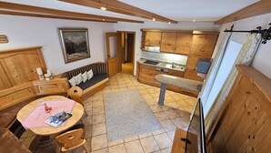 A kitchen with wooden cabinets, a dining table with chairs, a sofa, and a kitchen island.