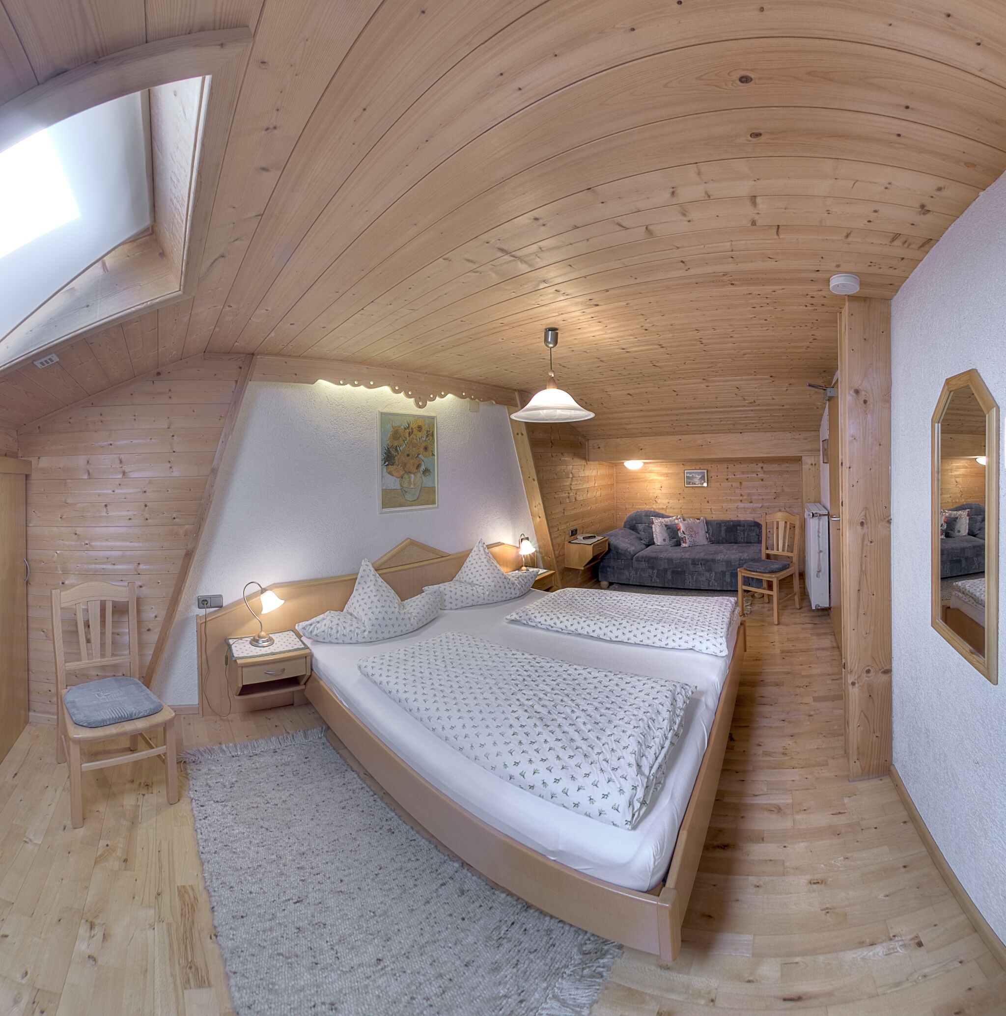 Een gezellig, houten interieur met een groot bed, een bank en een eethoek.