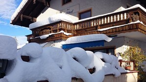 A snow-covered building with a balcony and a wooden fence. - Apartment Rauschbergblick 80 sqm, 2 separate bedrooms, bathroom, eat-in kitchen (Ruhpolding)