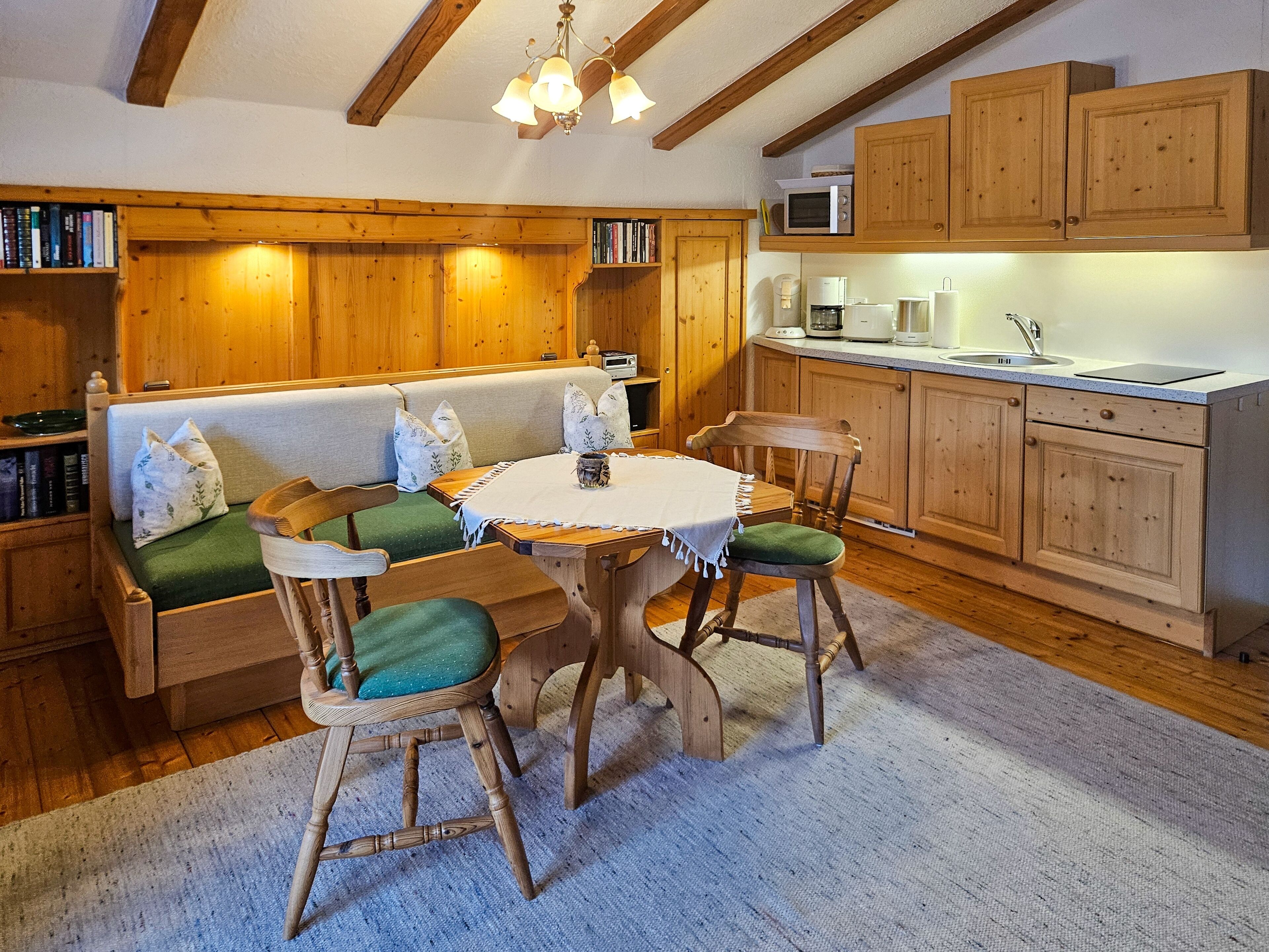Un ambiente accogliente in legno con un tavolo rotondo, sedie, un divano e un angolo cottura.