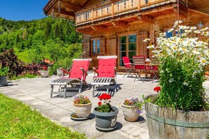A wooden chalet with a balcony, outdoor seating, and potted plants. - Ferienhaus "Hirschhäusl", Fam. Göppinger (Reit im Winkl)