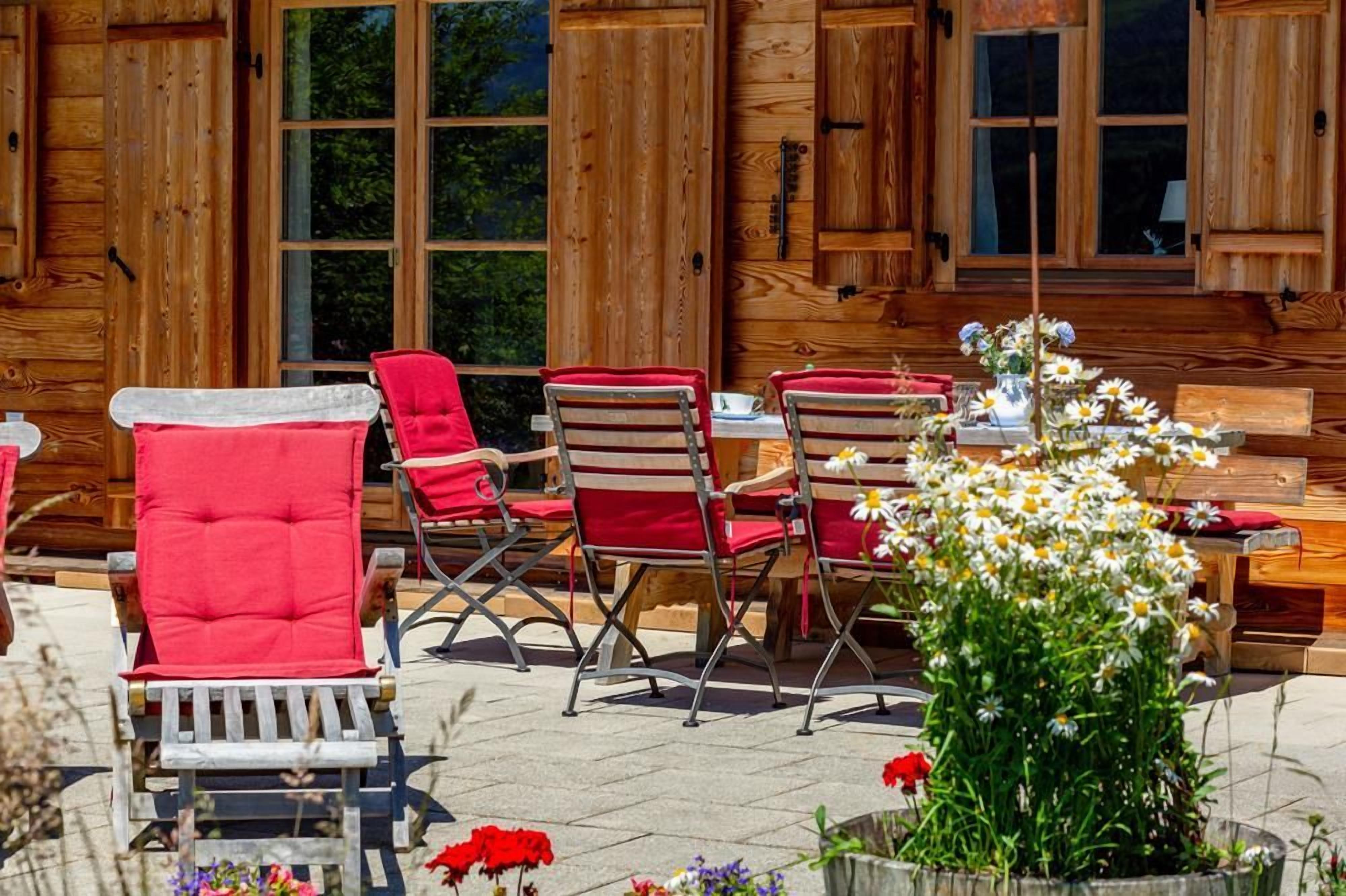 Una cabana de fusta amb un espai de pati que inclou seients exteriors i un arranjament floral.