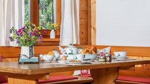 Ein Holztisch gedeckt mit einem Teekessel, Tassen, Tellern und einer Blumenvase.