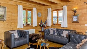 Ein gemütliches Blockhaus-Interieur mit zwei Ledersofas, einem Couchtisch und einem Kamin.