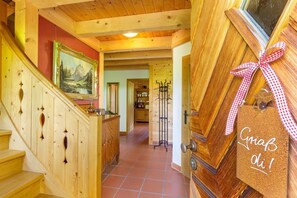 A wooden staircase with a painting on the wall, a door with a corkboard sign, and a hallway leading to a room. - Ferienhaus "Hirschhäusl", Fam. Göppinger (Reit im Winkl)