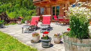 Eine Holzchalet mit einem Balkon, einer Sitzgelegenheit im Freien mit roten Stühlen und Blumentöpfen.