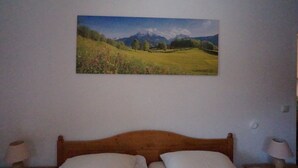 Une chambre à coucher avec un lit en bois, deux lampes de chevet et un tableau représentant un paysage accroché au mur.