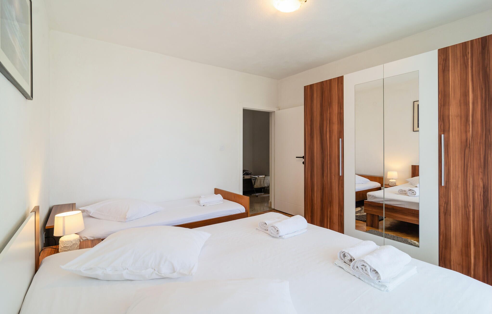 Une chambre d’hôtel avec deux lits, une armoire en bois et un miroir.
