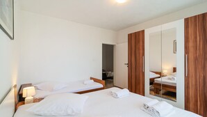 Et hotelværelse med to senge, et træskab og et spejl.