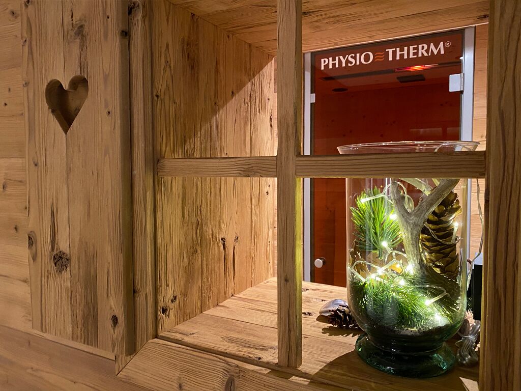 A wooden interior with a heart-shaped cutout, a glass display case with a plant, and a sign reading 'PHYSIO THERM'.