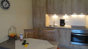 A kitchen with wooden cabinets, a stainless steel sink, a coffee maker, and an oven. - Apartment 4, 44sqm, 2 balconies, 1 bedroom, living room, kitchen, WLAN, TV (Ruhpolding)
