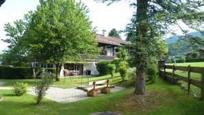 Un jardin bien entretenu, agrémenté d’un banc en bois, d’une balançoire et d’un petit espace de jeux.