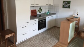 Une cuisine moderne avec des armoires blanches, un four encastré et un dosseret carrelé.