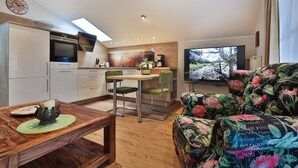 A compact living space with a kitchen, dining area, and a sofa with floral upholstery.
