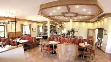 Un restaurante con cabinas y mesas redondas, techo de madera y una chimenea.